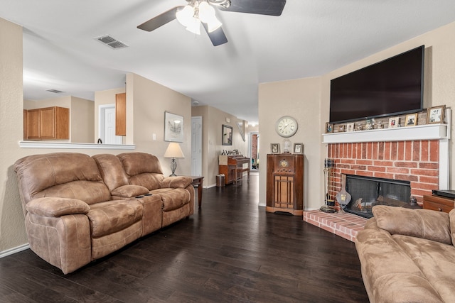 living room featuring ceiling fan, dark hardwood / wood-style floors, and a fireplace