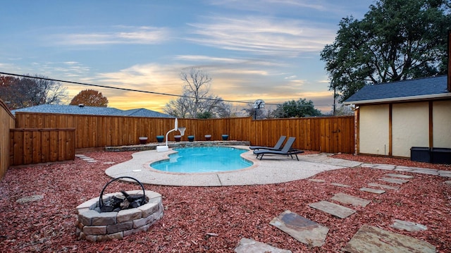 pool at dusk featuring an outdoor fire pit and a patio area