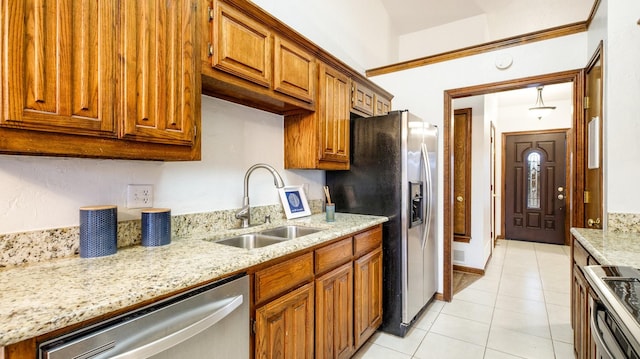 kitchen featuring light stone countertops, sink, light tile patterned floors, and stainless steel appliances