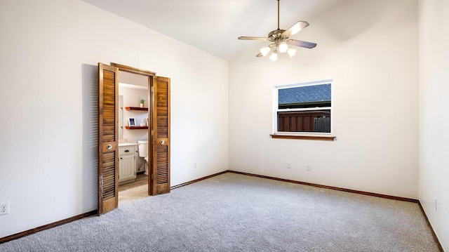 unfurnished bedroom featuring carpet flooring, ensuite bath, and ceiling fan