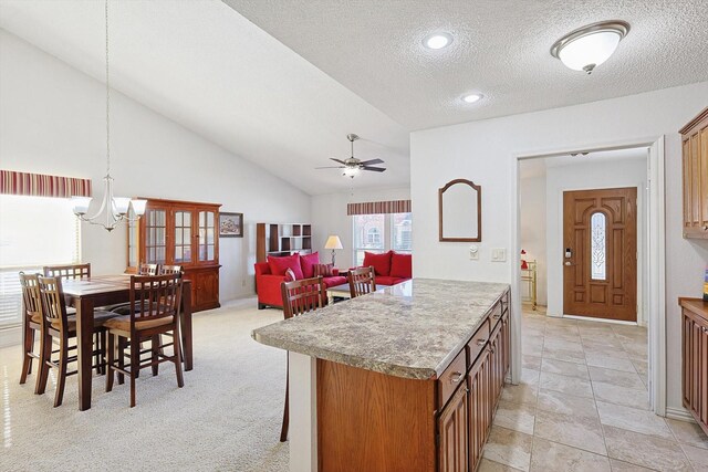 kitchen featuring pendant lighting, a textured ceiling, lofted ceiling, light carpet, and ceiling fan with notable chandelier