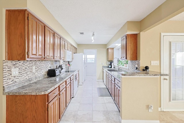 kitchen with backsplash, light tile patterned floors, stainless steel stove, and a textured ceiling