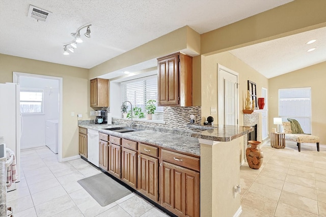 kitchen featuring white appliances, washing machine and dryer, a healthy amount of sunlight, and sink