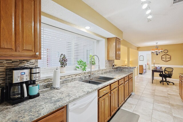 kitchen featuring white dishwasher, decorative backsplash, pendant lighting, and sink