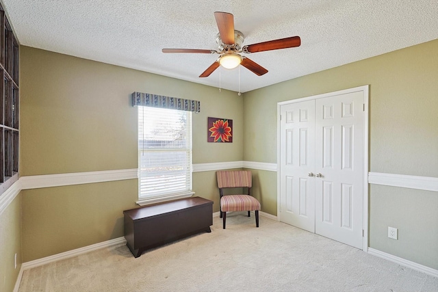 sitting room featuring a textured ceiling, light colored carpet, and ceiling fan