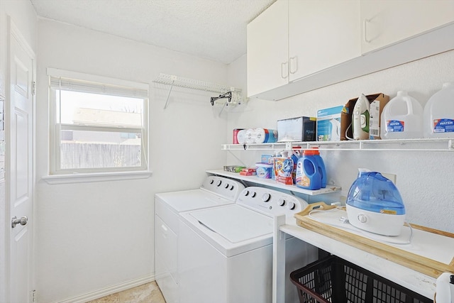 clothes washing area with cabinets, independent washer and dryer, a textured ceiling, and light tile patterned floors