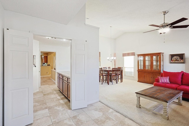 living room featuring light carpet, a textured ceiling, ceiling fan with notable chandelier, and vaulted ceiling