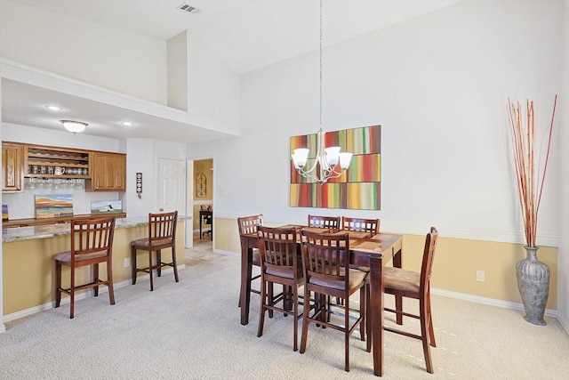 carpeted dining area featuring a towering ceiling and a notable chandelier