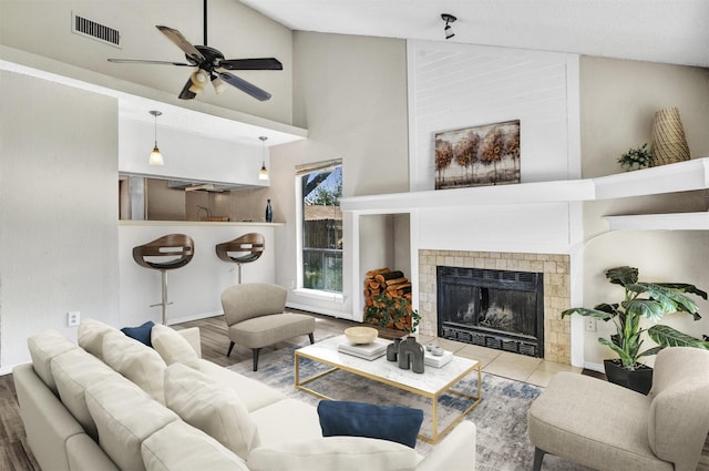 living room featuring a fireplace, hardwood / wood-style floors, high vaulted ceiling, and ceiling fan