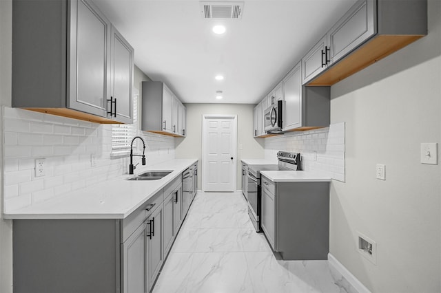 kitchen featuring decorative backsplash, appliances with stainless steel finishes, gray cabinetry, and sink