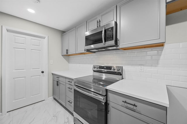 kitchen featuring appliances with stainless steel finishes, backsplash, and gray cabinetry