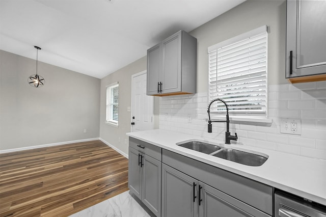 kitchen with decorative backsplash, sink, hardwood / wood-style flooring, gray cabinets, and hanging light fixtures