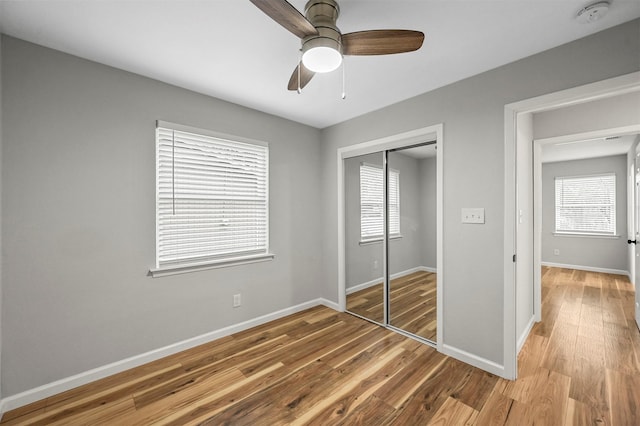 unfurnished bedroom featuring ceiling fan, a closet, and light wood-type flooring