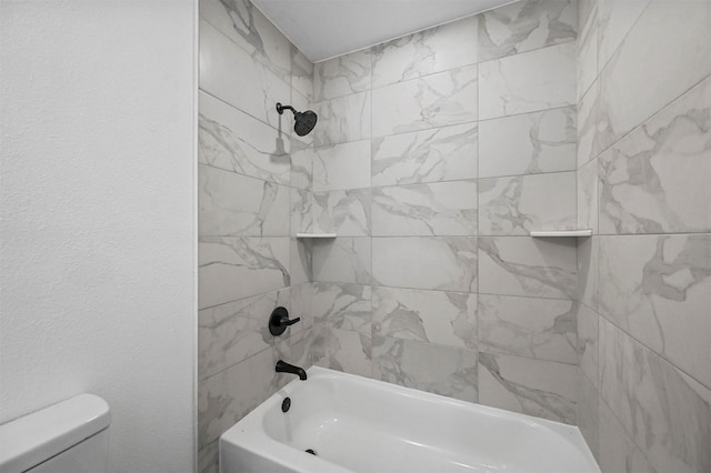 bathroom with toilet and tiled shower / bath