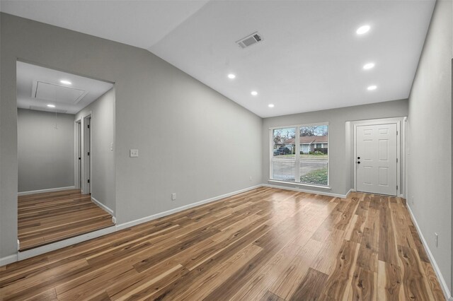 unfurnished living room with hardwood / wood-style floors and vaulted ceiling