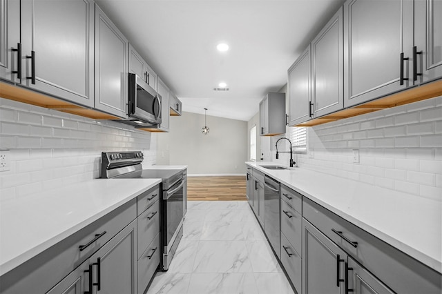 kitchen featuring gray cabinetry, decorative light fixtures, and appliances with stainless steel finishes