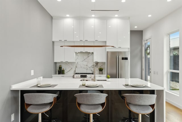 kitchen with white cabinetry, appliances with stainless steel finishes, a breakfast bar area, and a wealth of natural light