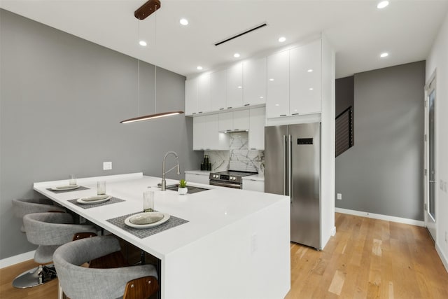 kitchen featuring sink, white cabinetry, appliances with stainless steel finishes, a kitchen breakfast bar, and pendant lighting