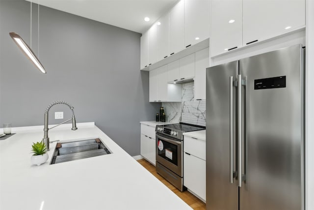 kitchen featuring sink, light hardwood / wood-style flooring, stainless steel appliances, tasteful backsplash, and white cabinets