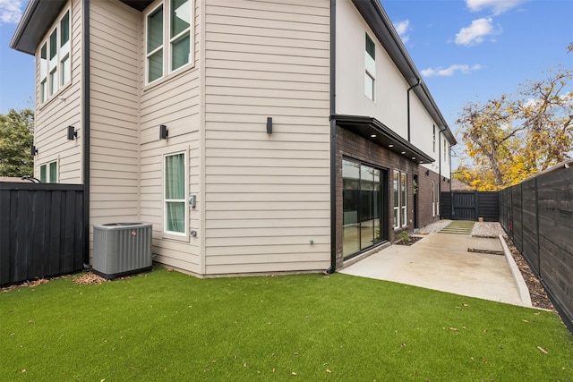 rear view of house with a patio area, central air condition unit, and a lawn