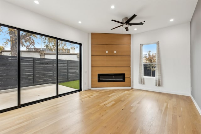 unfurnished living room featuring ceiling fan, a fireplace, and light hardwood / wood-style floors