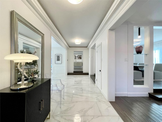 hall featuring marble finish floor, ornamental molding, and baseboards