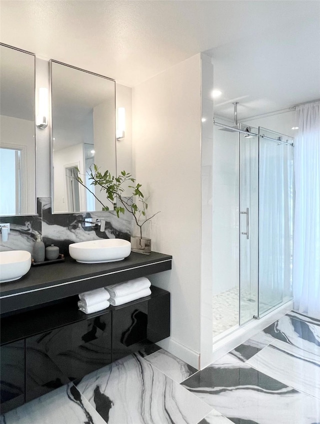 full bath with double vanity, marble finish floor, a shower stall, and a sink