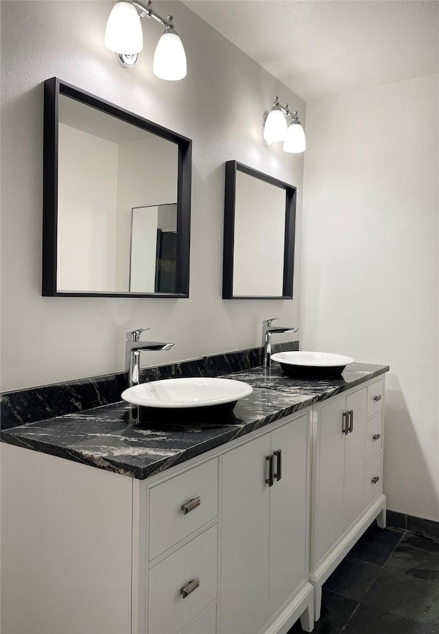 full bathroom featuring a sink, baseboards, and double vanity