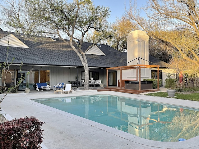 outdoor pool with an outdoor hangout area, a patio area, and a hot tub