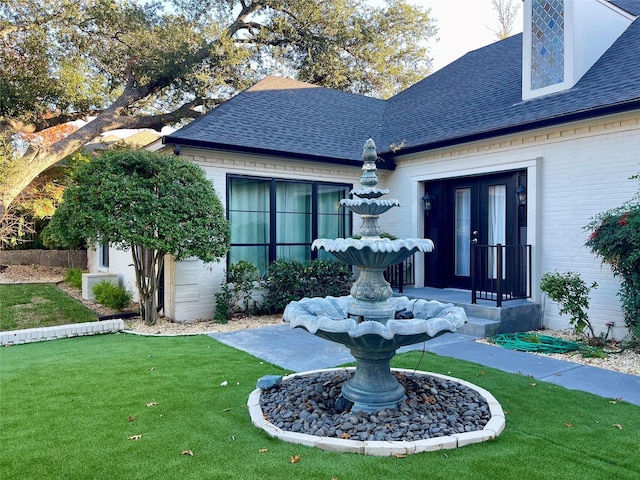 view of exterior entry featuring a lawn and french doors