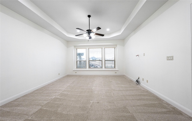 spare room featuring light colored carpet, ceiling fan, and a tray ceiling