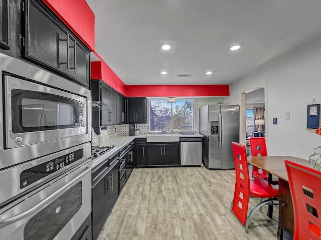 kitchen featuring sink, backsplash, stainless steel appliances, and light wood-type flooring