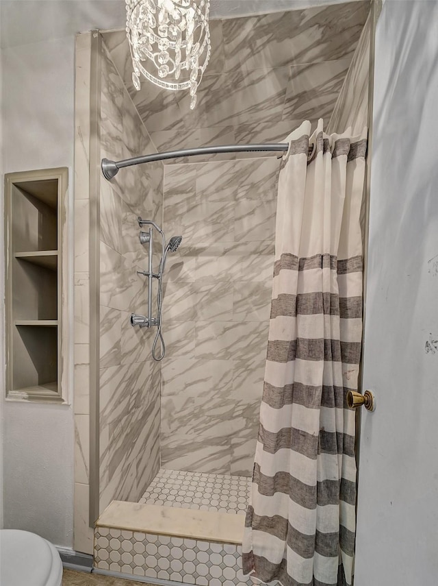 bathroom with a shower with curtain, toilet, and a chandelier