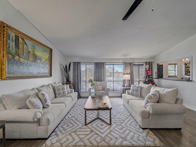 living room with hardwood / wood-style floors, ceiling fan with notable chandelier, and vaulted ceiling