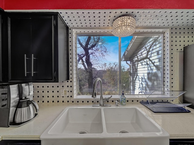 kitchen with backsplash, dishwasher, sink, and a chandelier