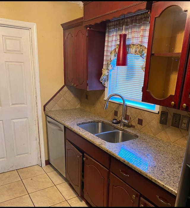 kitchen featuring sink, light tile patterned floors, dishwasher, light stone countertops, and decorative backsplash