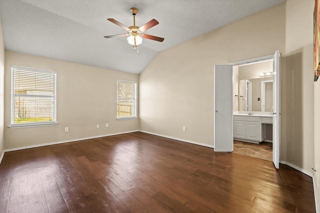 unfurnished bedroom with vaulted ceiling, ensuite bath, dark hardwood / wood-style flooring, ceiling fan, and a textured ceiling