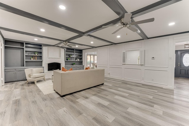 living room featuring built in shelves, light hardwood / wood-style floors, a brick fireplace, and a healthy amount of sunlight