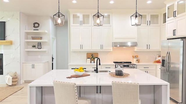 kitchen with range hood, light stone counters, white cabinetry, and appliances with stainless steel finishes