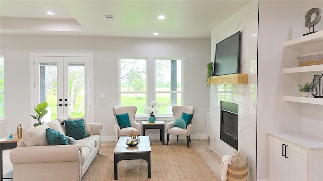 living room featuring light wood-type flooring, a fireplace, and french doors