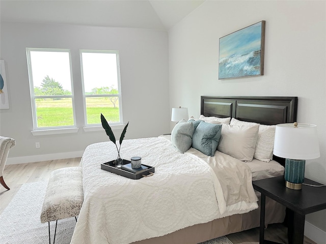 bedroom with wood-type flooring and vaulted ceiling