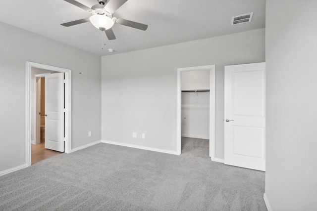 unfurnished bedroom with carpet flooring, a closet, a spacious closet, and ceiling fan