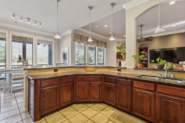 kitchen featuring decorative light fixtures, ceiling fan, dark stone counters, and sink