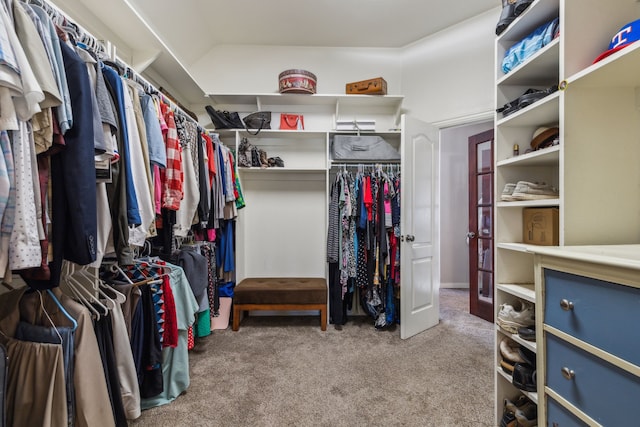 walk in closet with light carpet