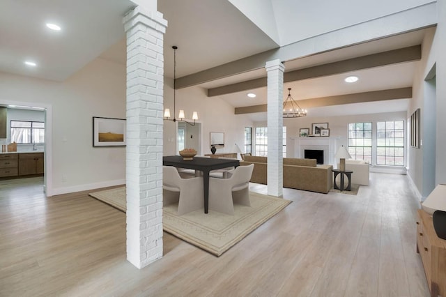 dining space with ornate columns, vaulted ceiling with beams, and an inviting chandelier