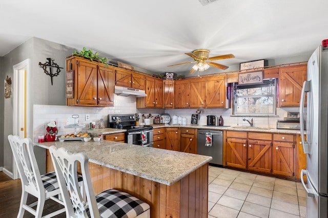 kitchen featuring sink, a kitchen breakfast bar, kitchen peninsula, light tile patterned floors, and appliances with stainless steel finishes