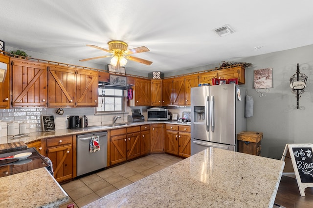 kitchen with ceiling fan, light stone countertops, sink, and appliances with stainless steel finishes