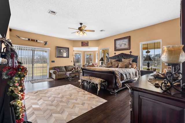 bedroom with access to exterior, a textured ceiling, ceiling fan, and dark wood-type flooring