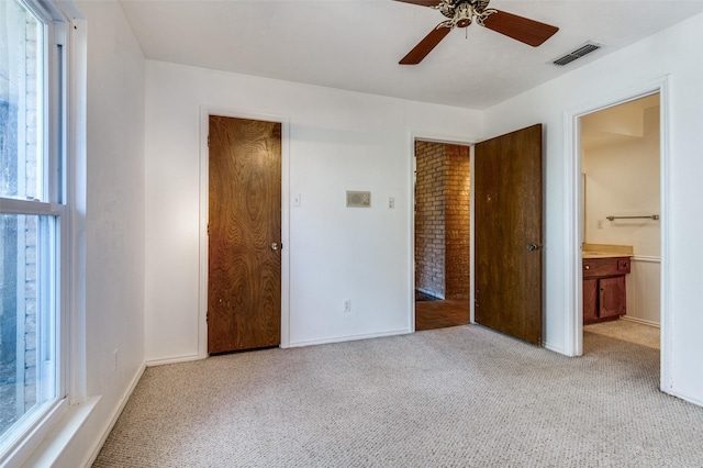 unfurnished bedroom with ensuite bath, light carpet, ceiling fan, and multiple windows