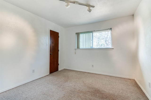 carpeted empty room featuring track lighting